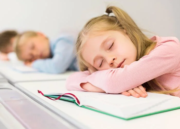 una niña durmiendo en una mesa con los ojos cerrados Problemas de sueño más frecuentes en niños