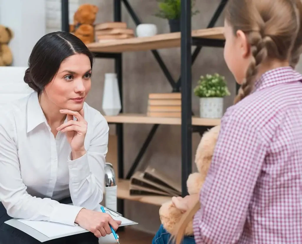 una mujer sentada en una silla sosteniendo un portapapeles y sosteniendo un osito de peluche